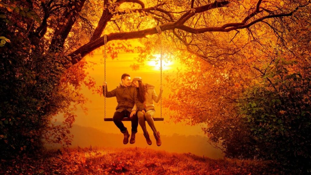 young couple on tree swing in autumn forest
