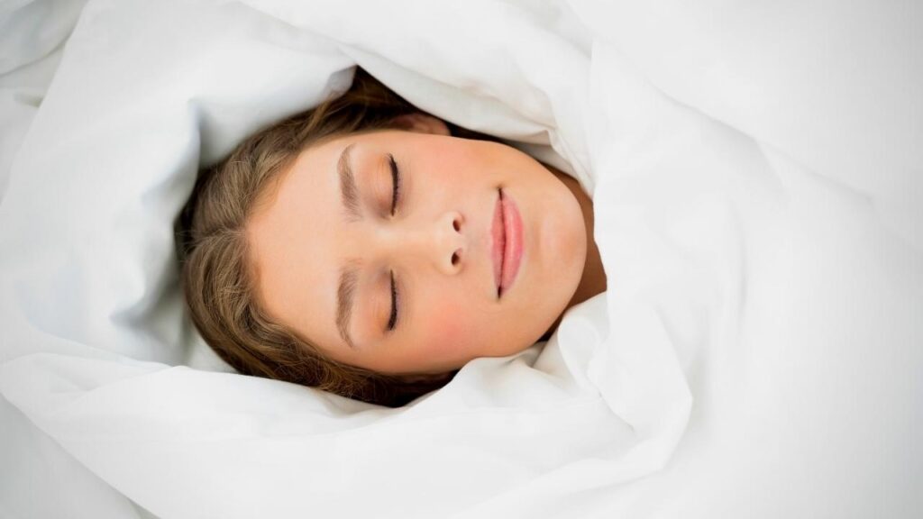 woman's face cocooned by duvet