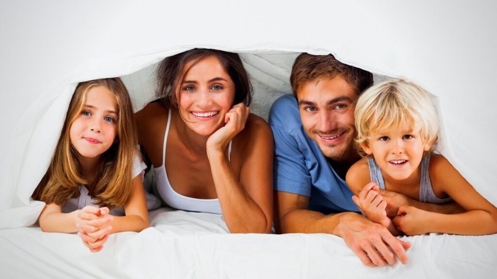 family looking out from under the duvet