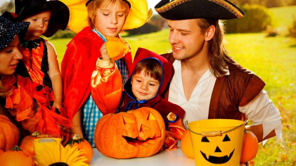 Family in halloween costumes carving pumpkins