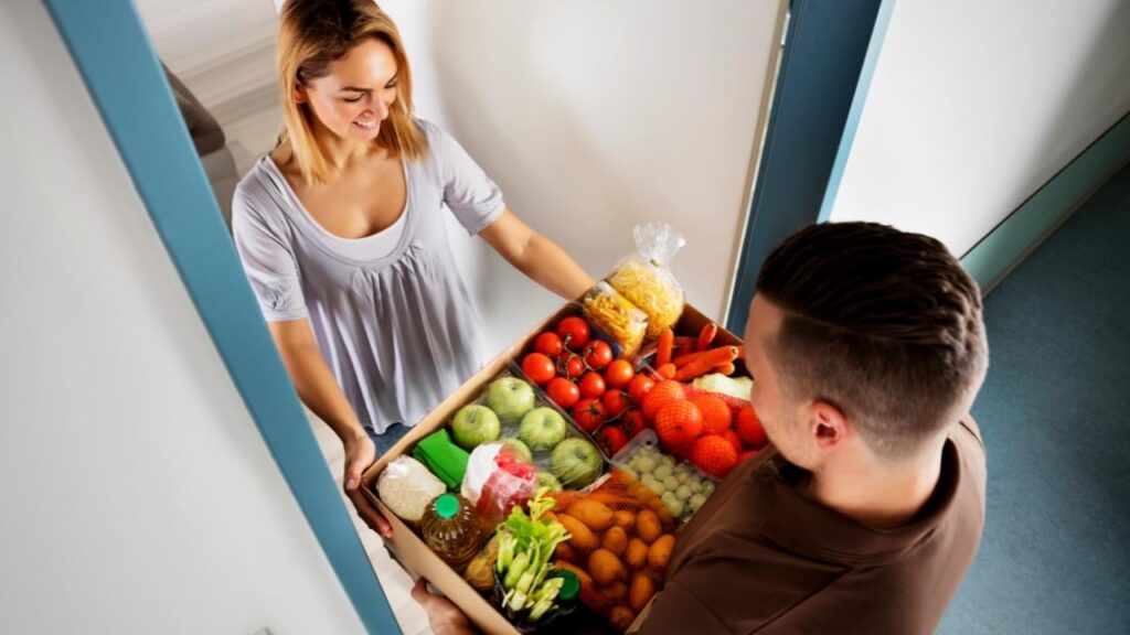 man handing box of produce to lady