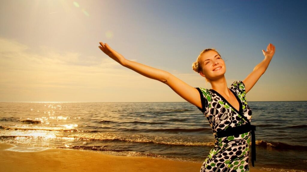 woman on beach stretching arms up