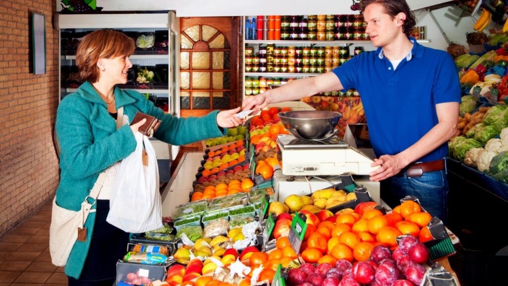 lady buying fruit from male greengrocer