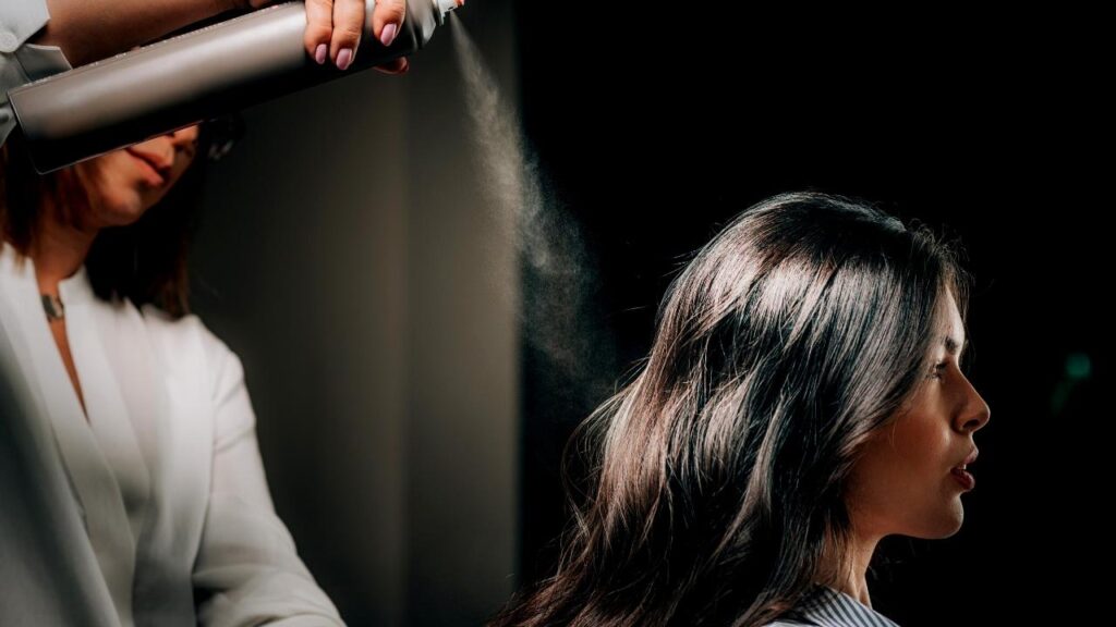 hairdresser spraying woman's black hair