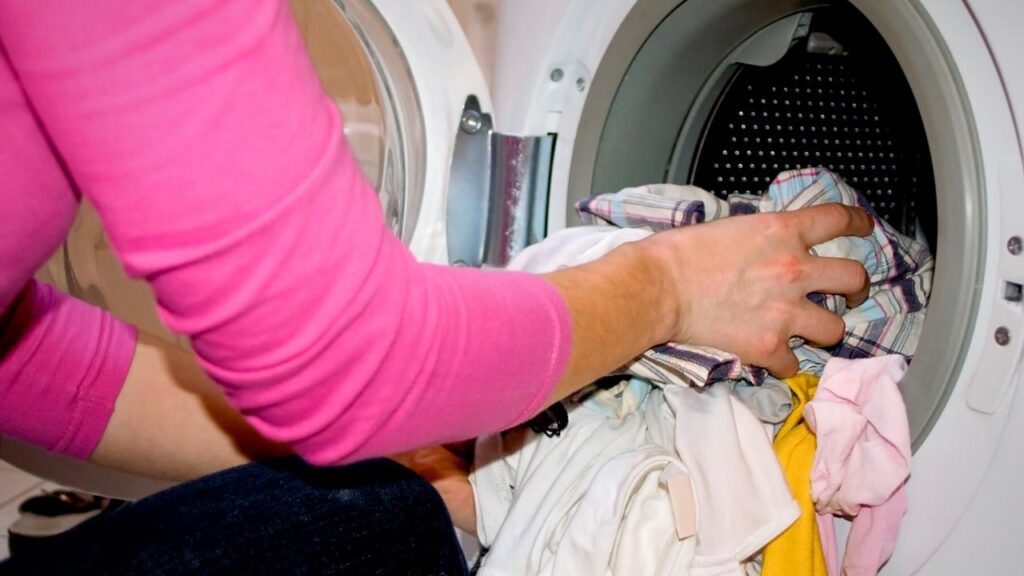 woman putting clothes in washing machine