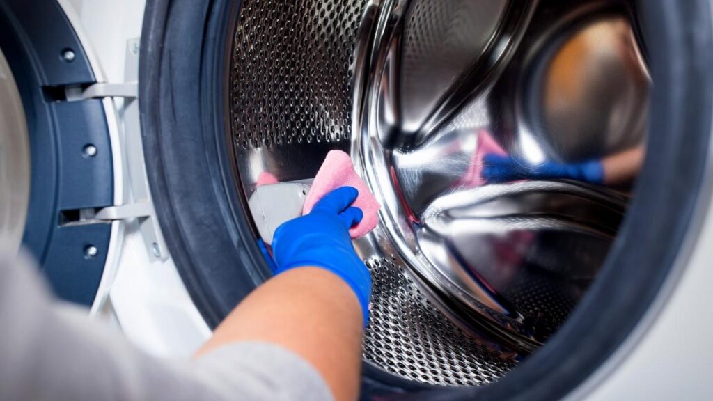 reaching into washing machine with cloth