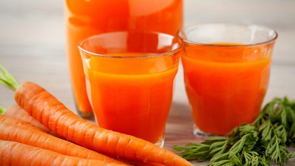 glasses of carrot juice beside carrots