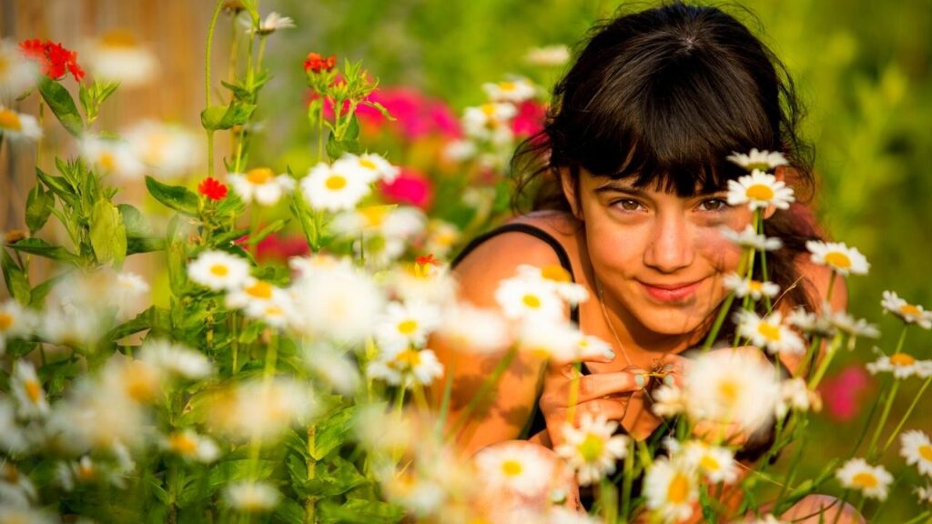teen girl crouching among wildflowers